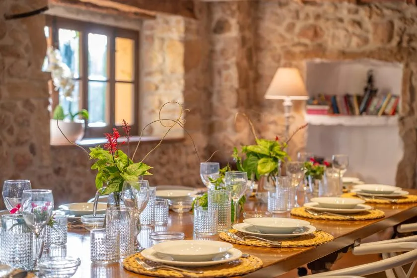 A stone-walled dining room with a long table set for a meal.