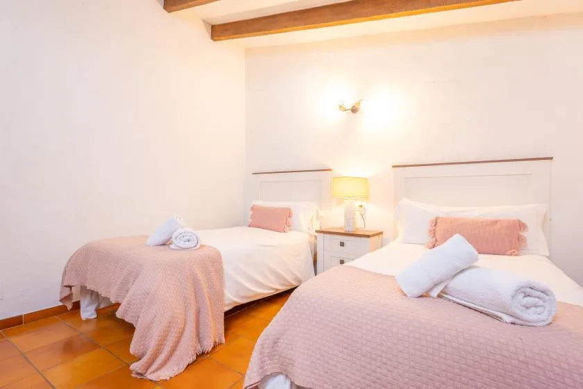 A bedroom with two beds and a bedside table between them.