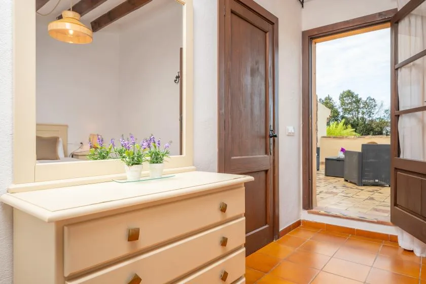 A bedroom dressing area with a cream dresser and an open doorway to a patio.