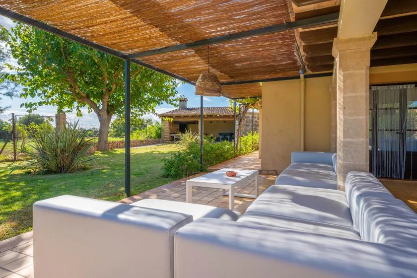 A covered patio with outdoor seating and a garden view.