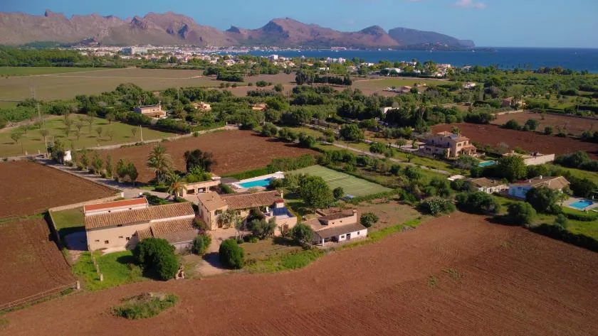 An aerial view of agricultural fields and homes with a coastal mountain range in the distance.