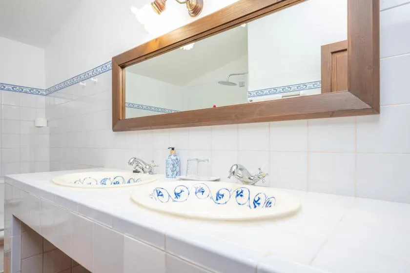 A tiled bathroom vanity with two sinks and a large wall mirror.