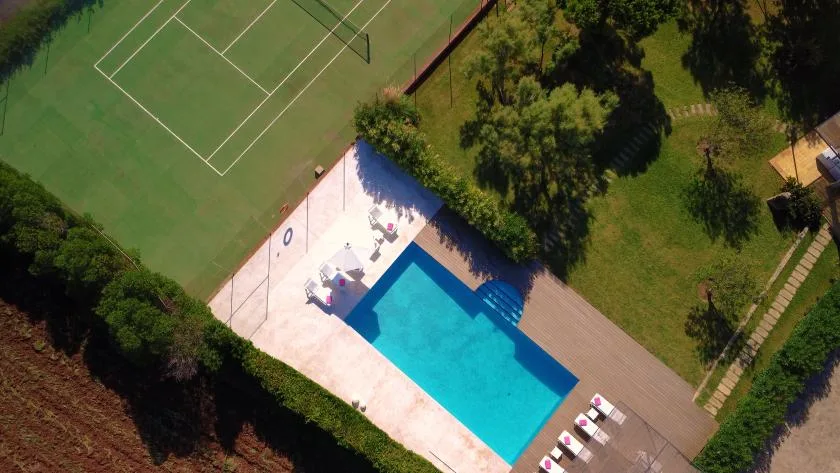 An aerial view shows a swimming pool beside a green sports court.