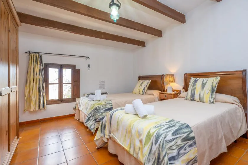 A bedroom with two beds, patterned bedding, and a window.