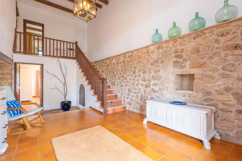 A spacious interior features a staircase beside a stone wall and tiled floor.