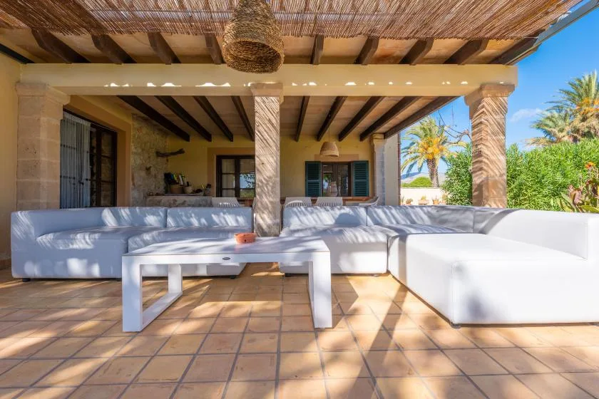 A covered outdoor seating area with a low table and garden views.