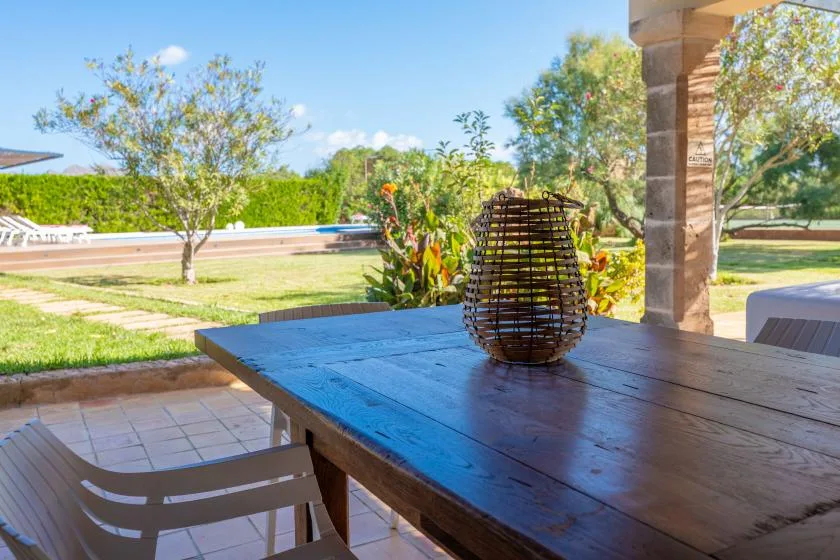 An outdoor dining table overlooks a landscaped garden and swimming pool.