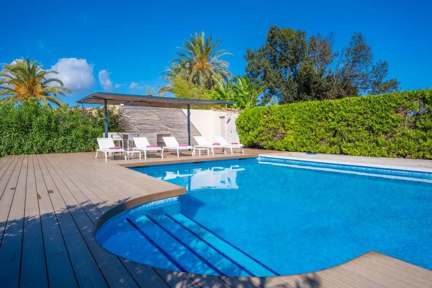 An outdoor swimming pool beside a wooden deck and lounge seating.