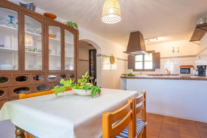 A bright kitchen and dining area with a table, wooden chairs, and cabinets.