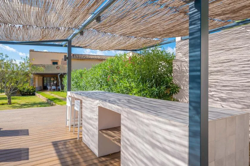 A shaded outdoor patio with a built-in counter and surrounding greenery.
