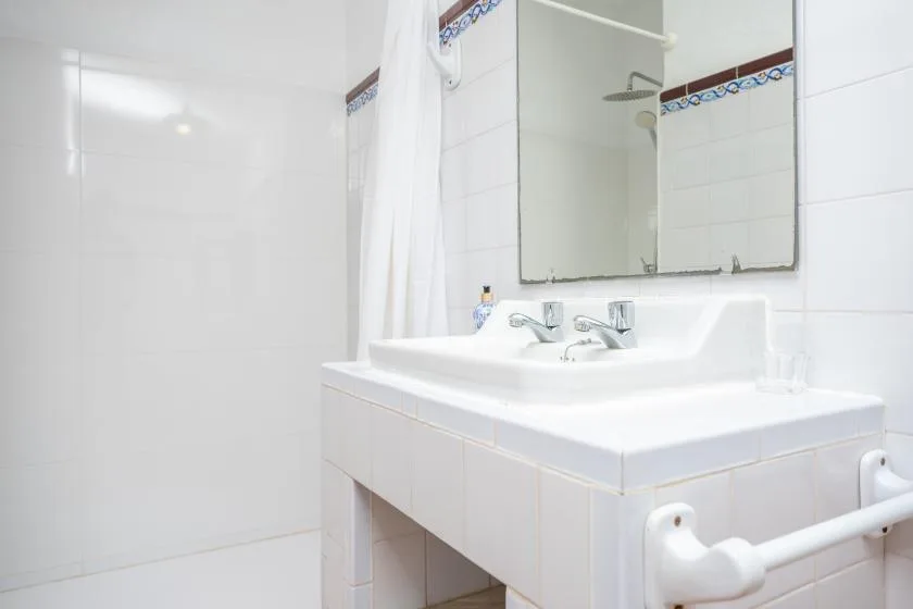 A bright bathroom with a white sink and a shower curtain.