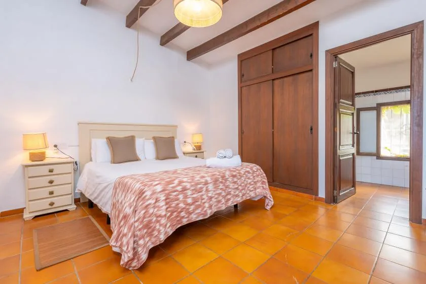 A bedroom with a bed, bedside tables, and a wooden wardrobe.