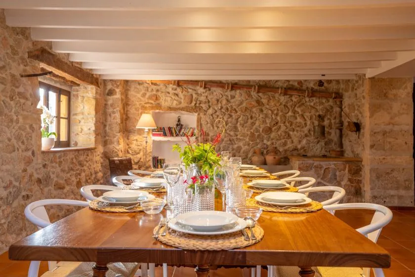 A dining room with a long table set with plates and flowers.