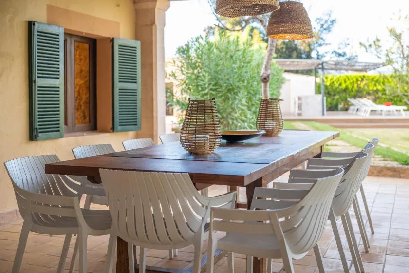 An outdoor dining area with a long table and chairs beside a house.