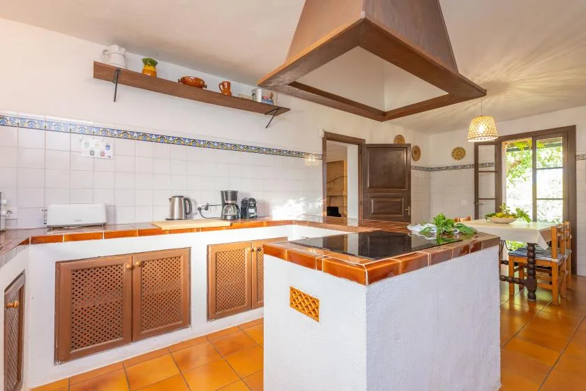 A tiled kitchen with a central counter and a dining table by the window.