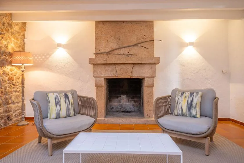 A sitting area with two cushioned chairs facing a stone fireplace.