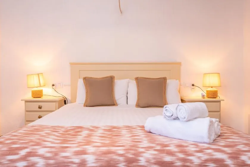 A bedroom with a neatly made bed, pillows, and bedside lamps.