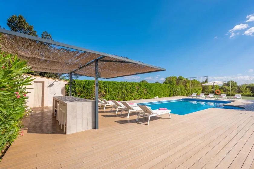 An outdoor pool and surrounding deck sit beside a shaded seating area.