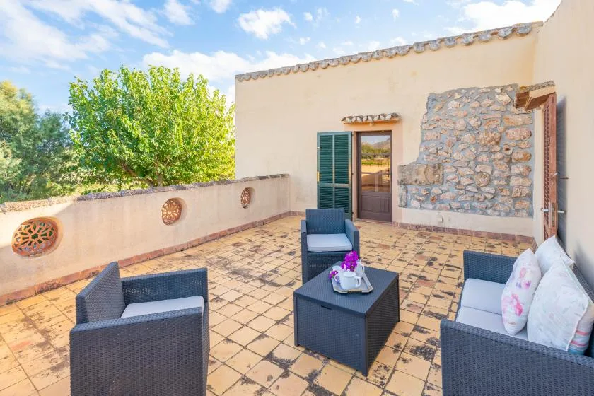 A tiled outdoor seating area with dark wicker furniture and a low table.
