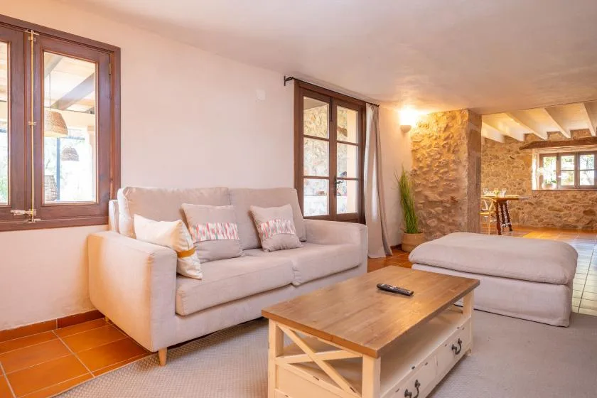 A living room with upholstered seating, a wooden coffee table, and windows.