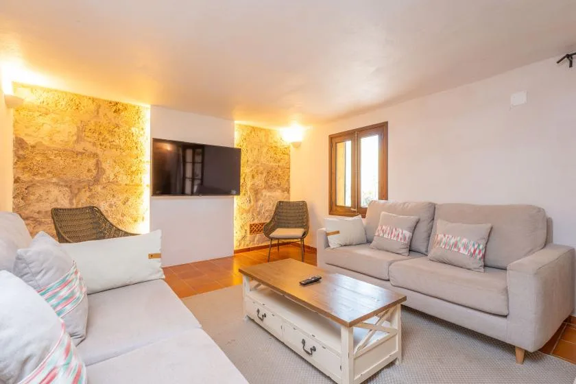 A living room with sofas, a coffee table, and a television on the wall.