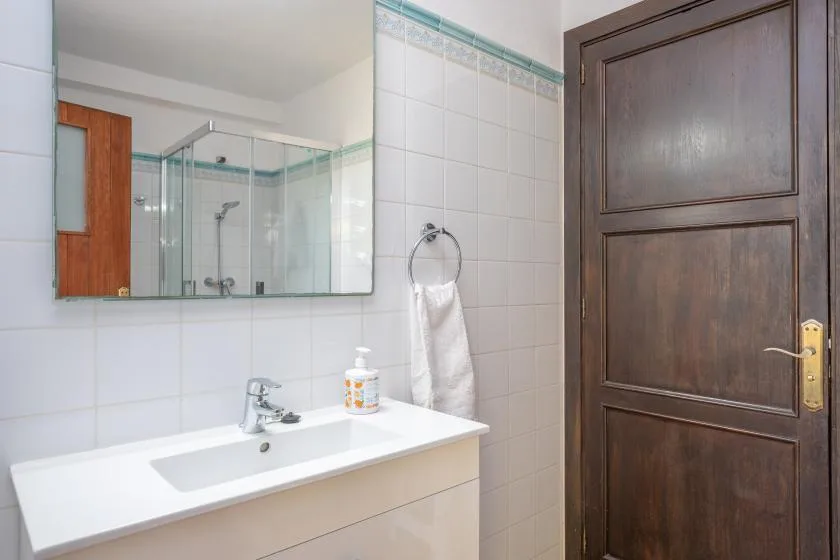 A bathroom with a white sink, tiled walls, and a dark wooden door.