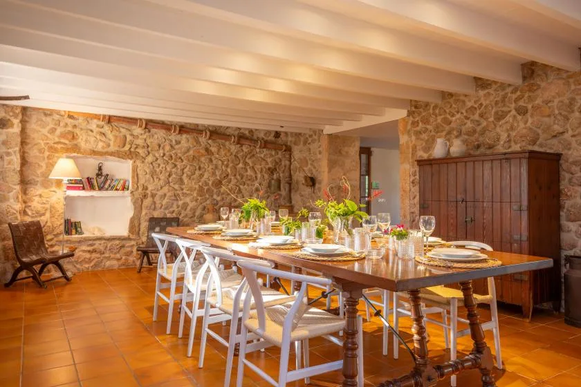 A rustic dining room with a long table set for a meal.