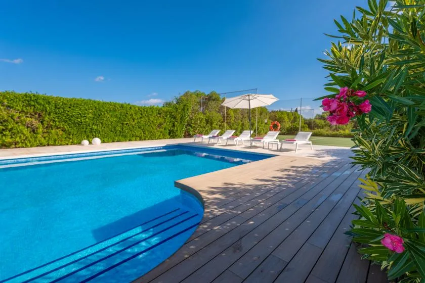 An outdoor swimming pool beside a wooden deck and lounge seating.