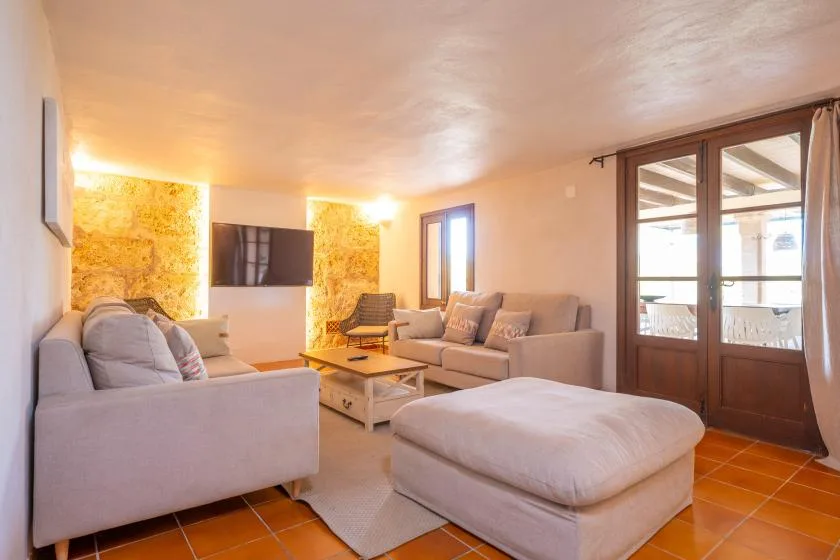 A bright living room with light-colored seating and glass doors opening onto a balcony.