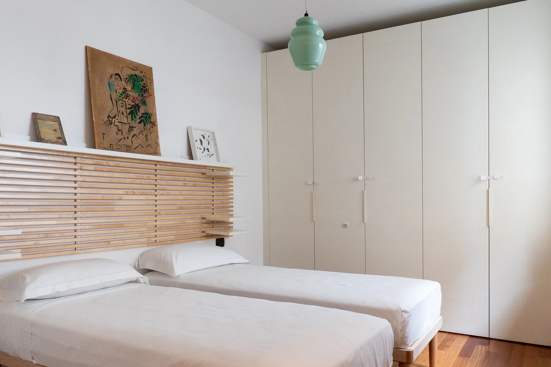 Un dormitorio con dos camas, ropa de cama blanca y armarios empotrados.