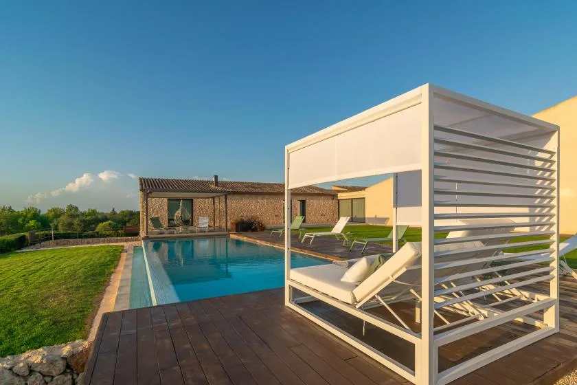 A swimming pool beside a wooden deck and a shaded seating area.