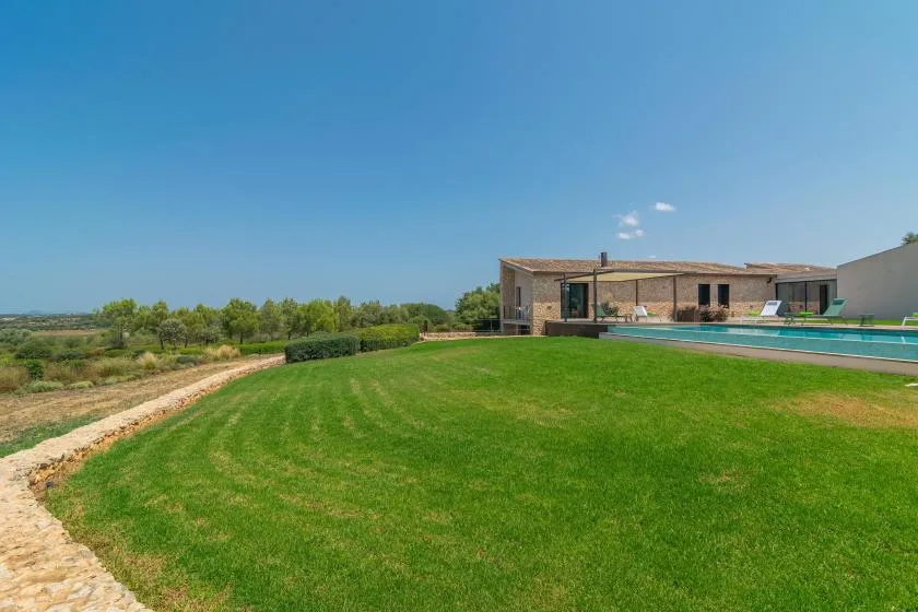 A modern house and swimming pool sit beyond a broad green lawn.