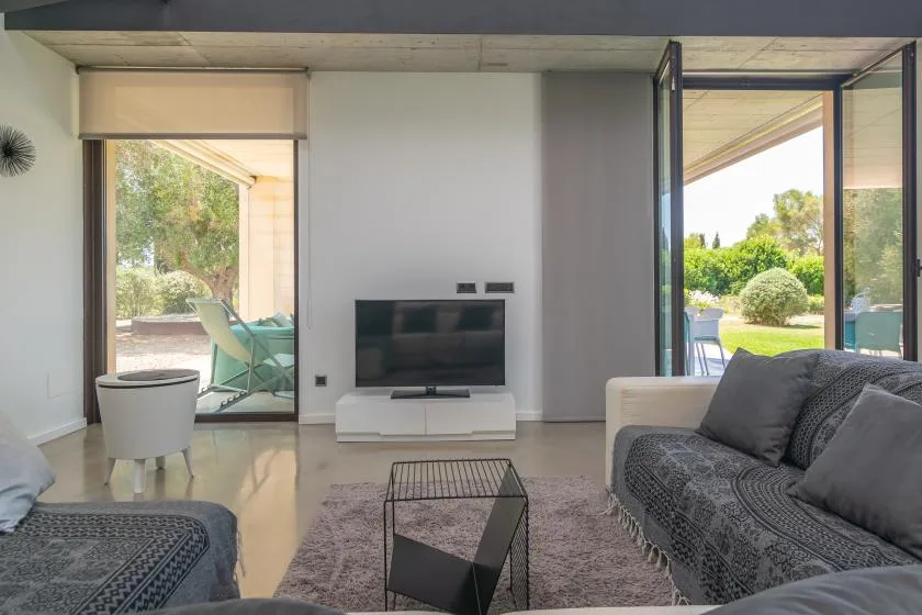 A living room with a television and seating beside open glass doors.