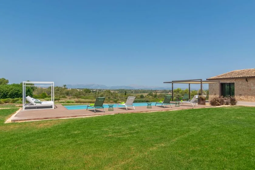 An outdoor pool beside a green lawn and a stone building.