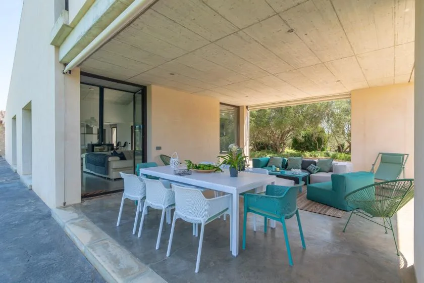 A covered outdoor dining and seating area opens onto a leafy garden.