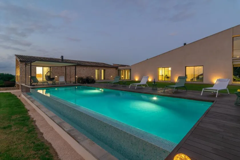 An outdoor swimming pool beside a modern building at dusk.
