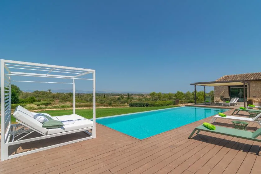 An outdoor swimming pool is surrounded by a wooden deck and lounge seating.