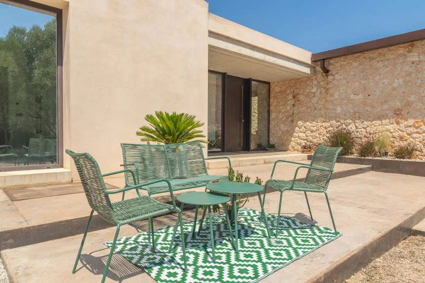 An outdoor patio with green seating arranged around a small table.