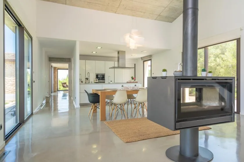 A bright open-plan kitchen and dining area features a central island and freestanding fireplace.