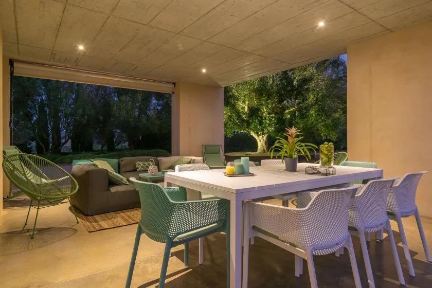A covered outdoor dining and seating area opens onto a leafy garden.