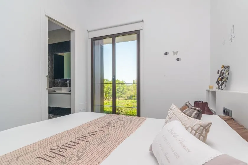 A bedroom with a bed and sliding glass doors opening onto a green view.