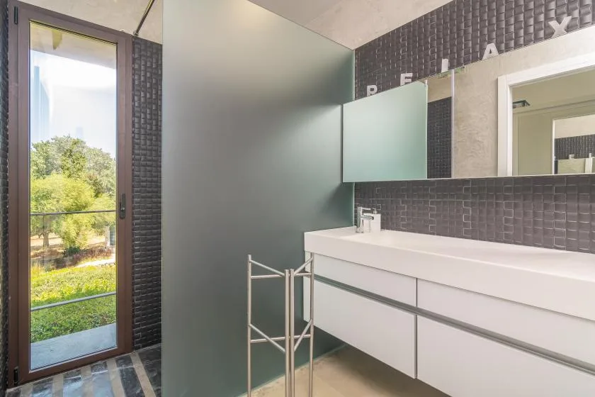 A modern bathroom with a long vanity, mirror, and glass shower partition.