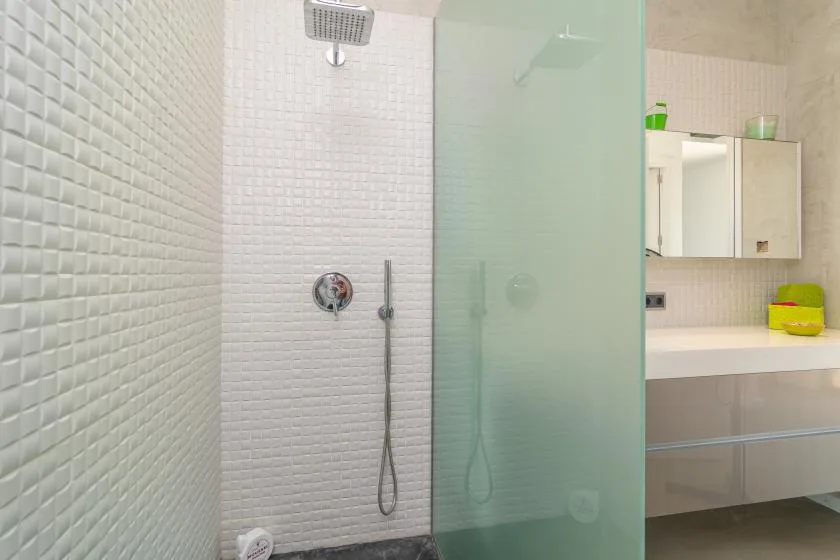 A tiled bathroom shower area with a glass screen and vanity.