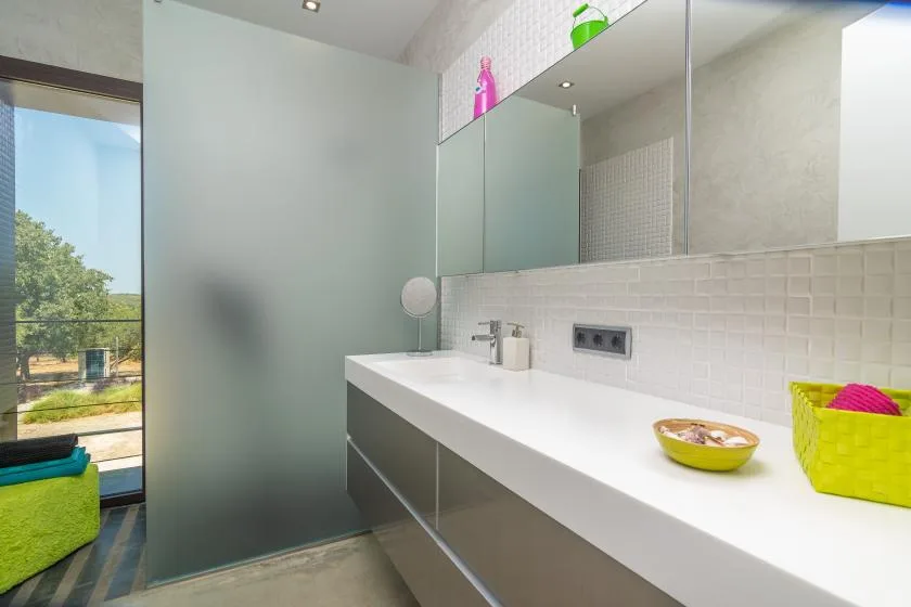 A modern bathroom with a long white vanity and a large mirror.