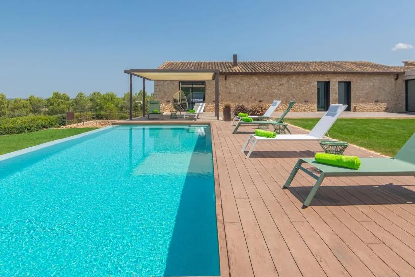 An outdoor swimming pool beside a wooden deck with loungers.