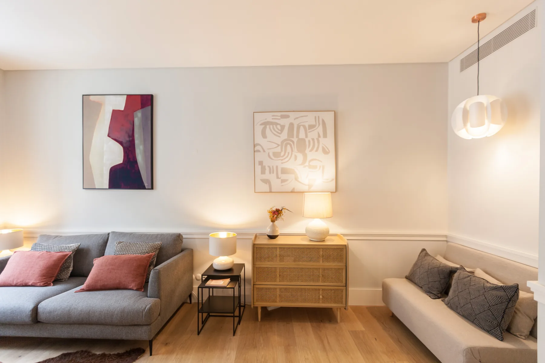 Una sala de estar con asientos, arte en las paredes y un mueble central.