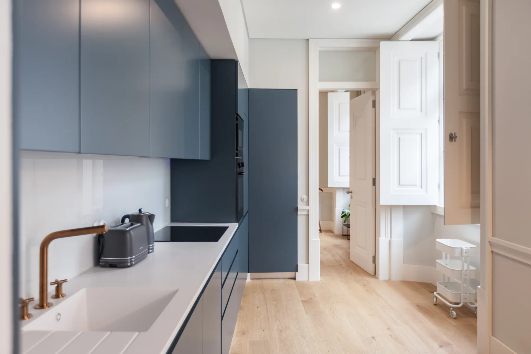Una cocina luminosa con gabinetes azules y una encimera blanca.