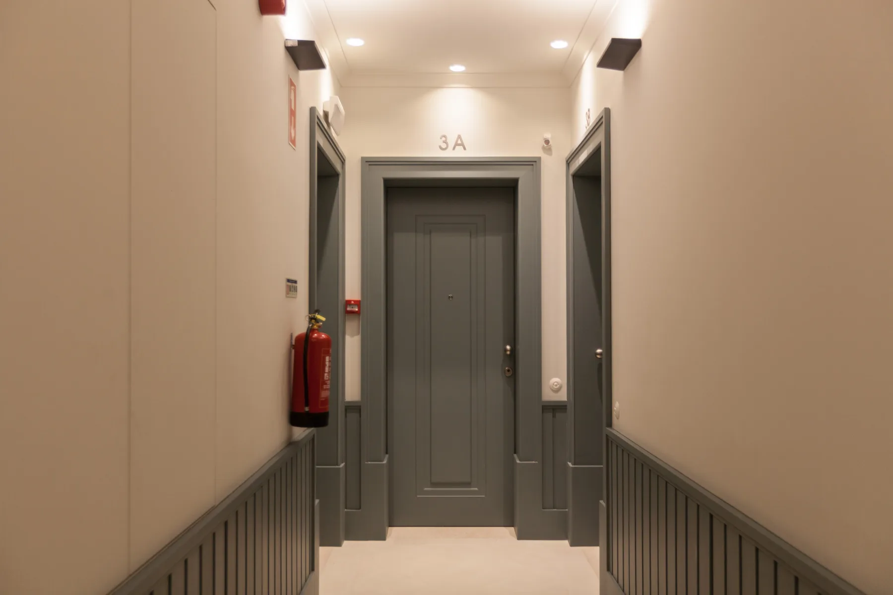 Un pasillo con una puerta gris al fondo.