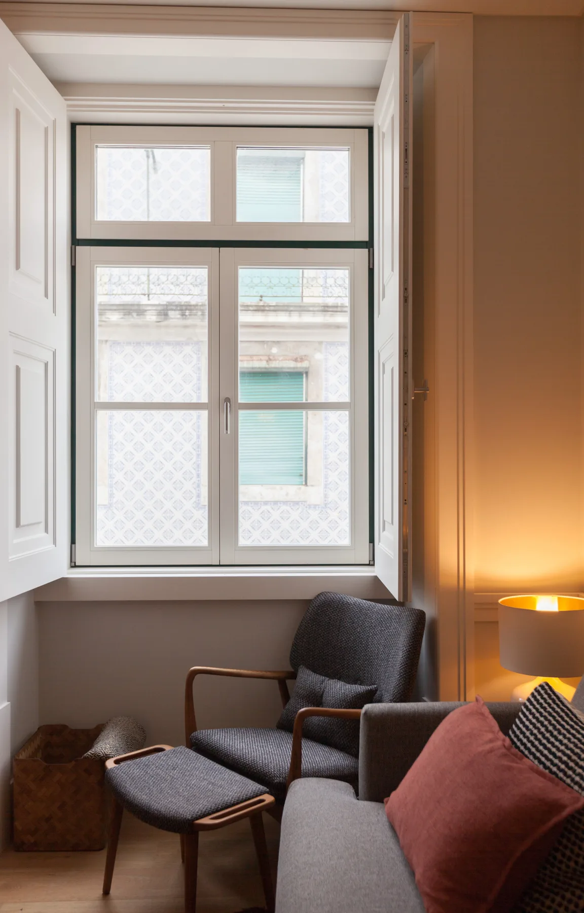 Una zona de estar junto a una ventana grande, con un sillón y un sofá.