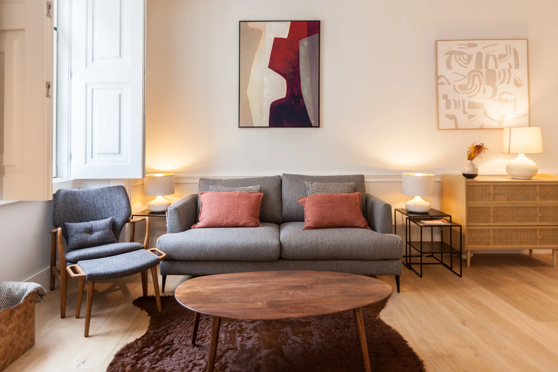 Una sala de estar con sofá, sillón y cuadros enmarcados.